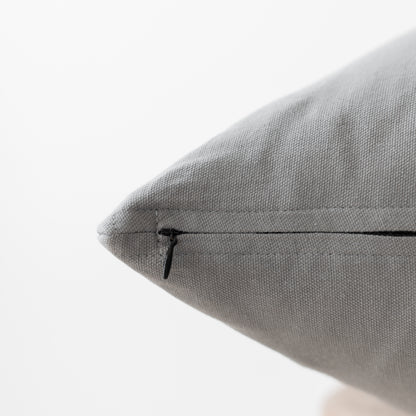 Gray textured pillow with concealed zipper closure, close-up detail view.