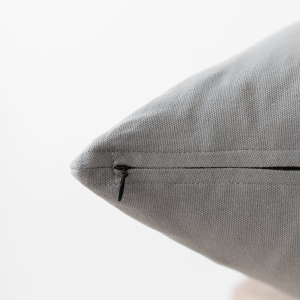Gray textured pillow with concealed zipper closure, close-up detail view.