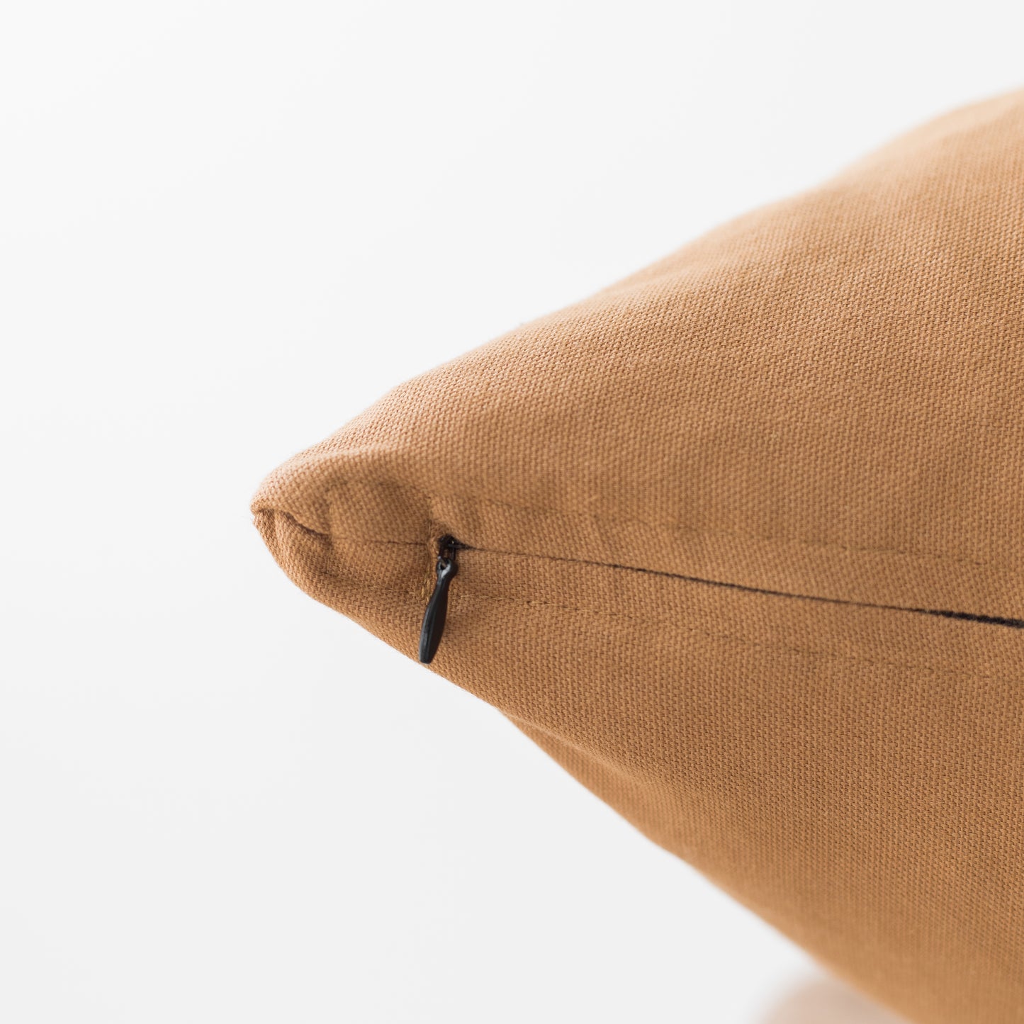 Terracotta-colored woven pillow with zipper closure and textured fabric surface.