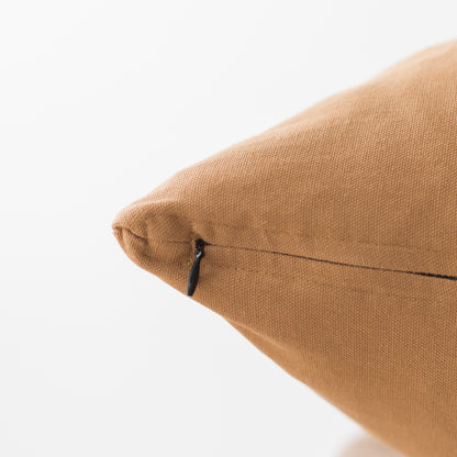 Terracotta-colored woven pillow with zipper closure and textured fabric surface.