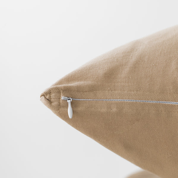 Tan linen pillow with white zipper closure on side seam.