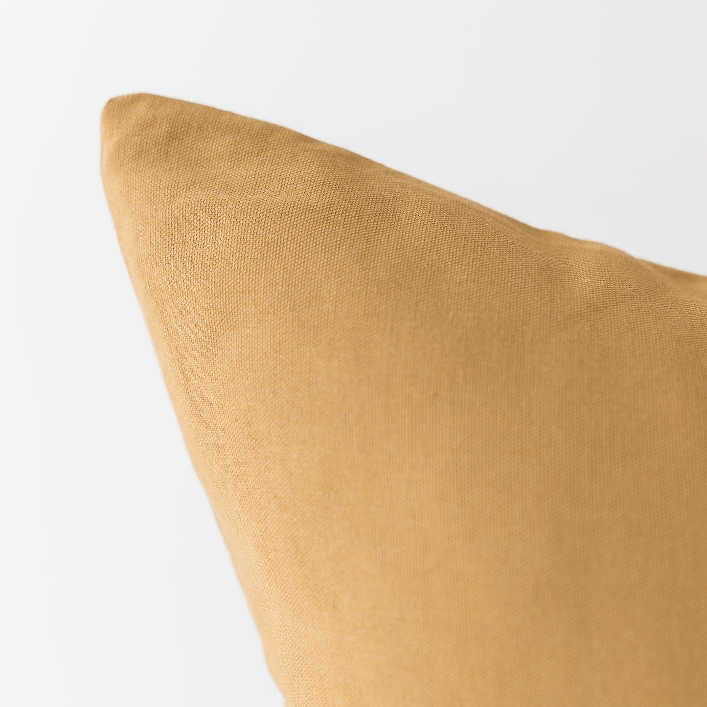 Gold-colored woven pillow cover with plain texture against a light background.