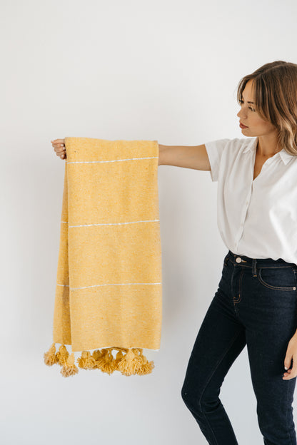 Yellow throw blanket with white stripe pattern and tassel fringe ends.