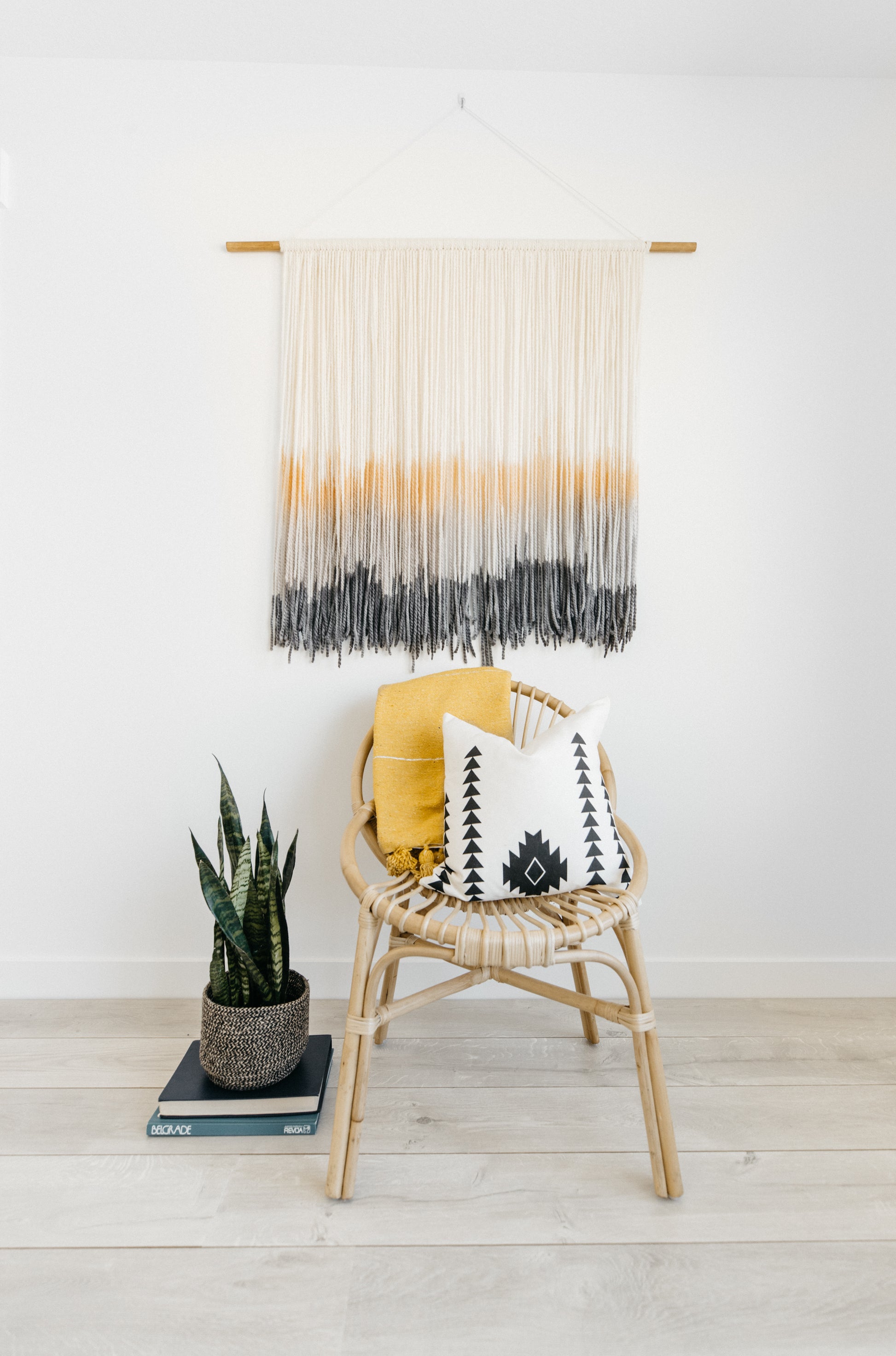 Cream, gold, and charcoal ombre macramé wall hanging with wooden dowel and rope fringe.