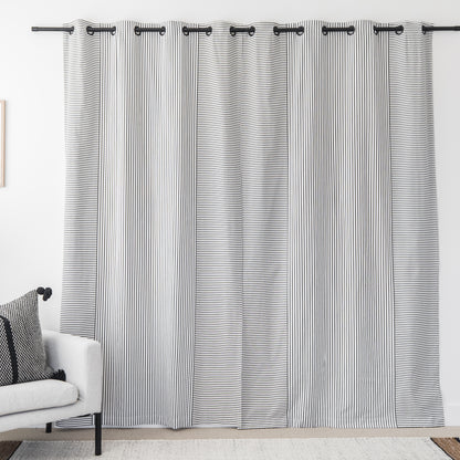Two white curtain panels with fine black vertical stripes and grommet tops hanging on a black rod.