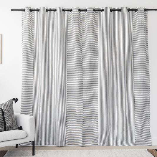 Two white curtain panels with fine black vertical stripes and grommet tops hanging on a black rod.