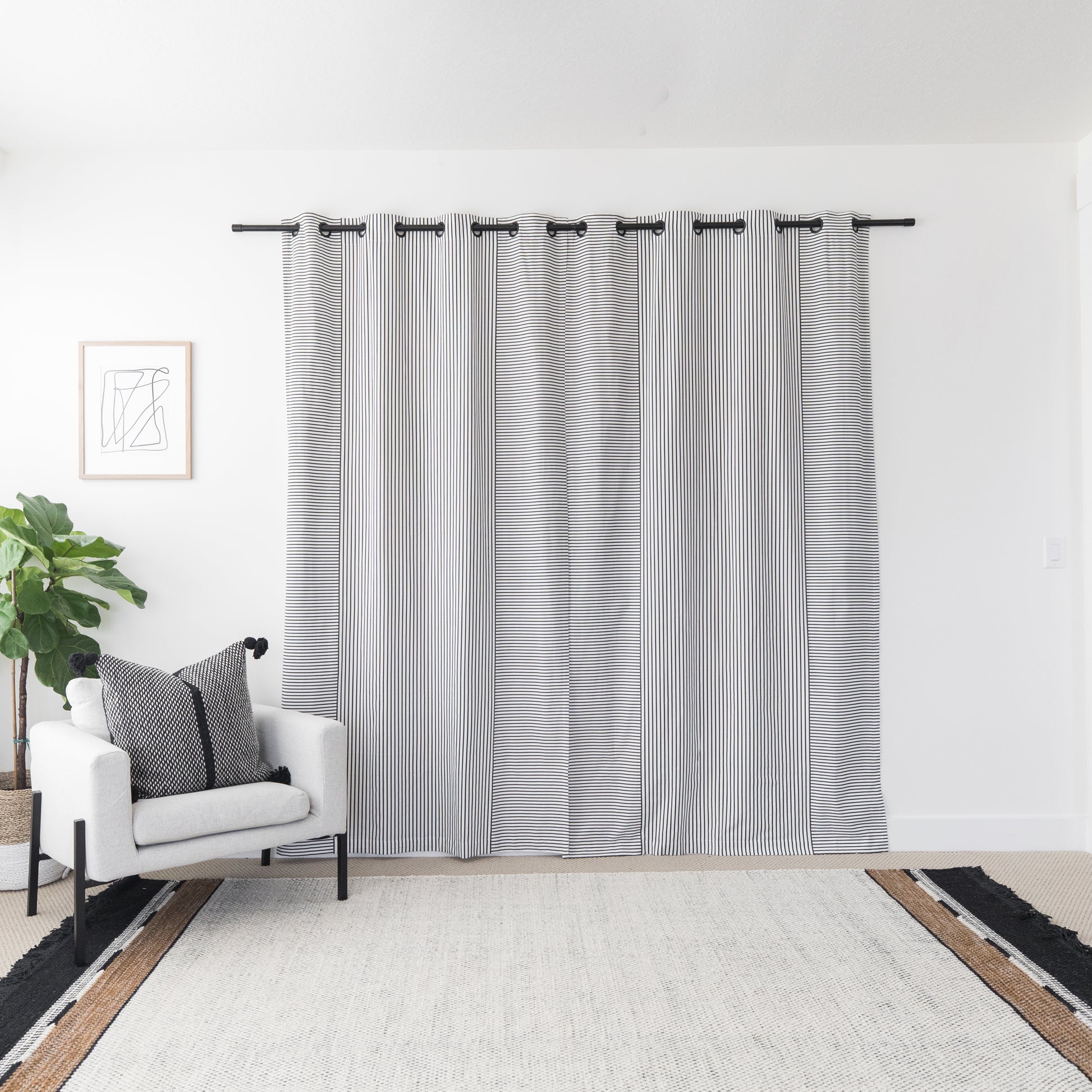 Two white curtain panels with vertical gray stripes, featuring grommet tops, hanging on a dark rod.