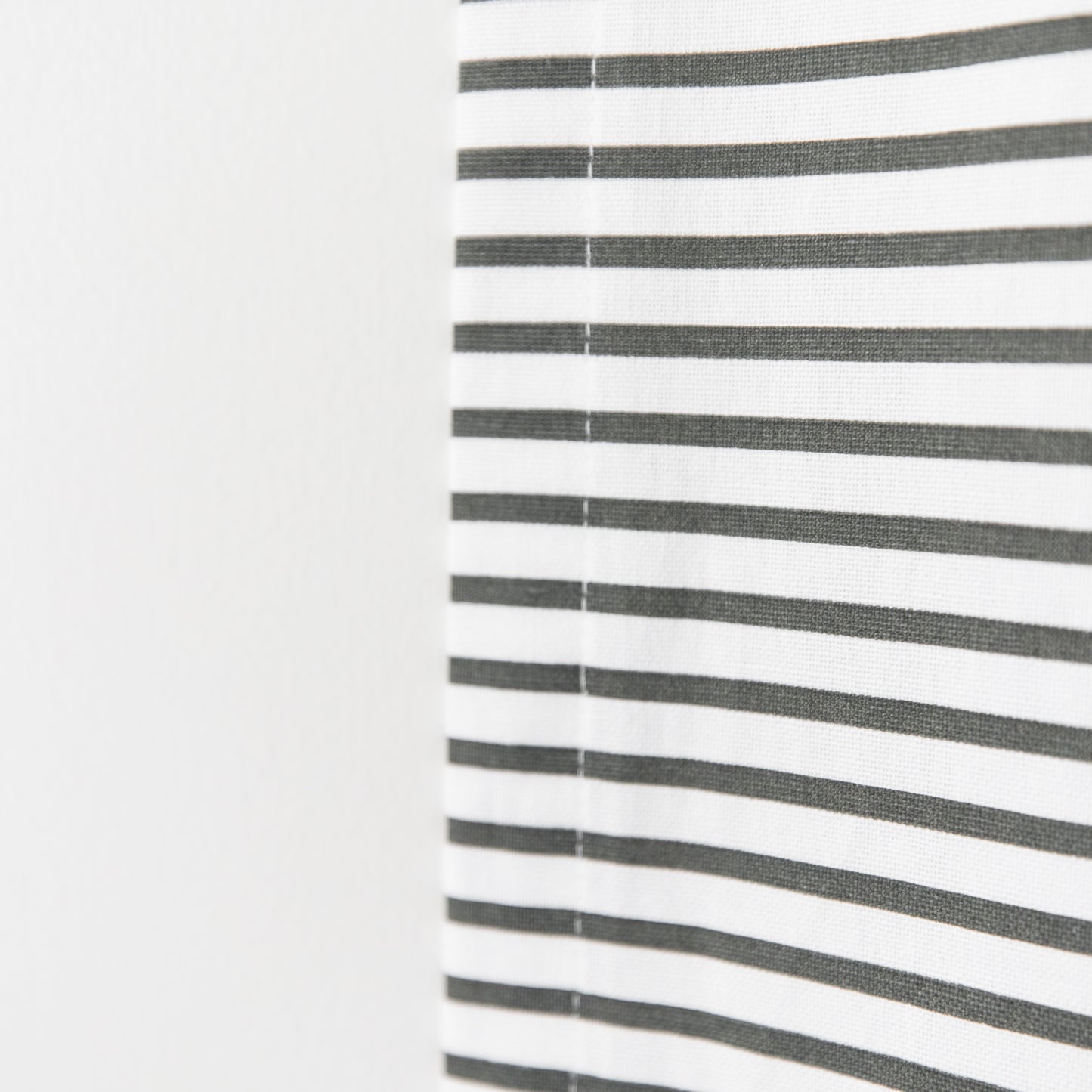 White curtain panel with evenly spaced horizontal gray stripes and center seam.