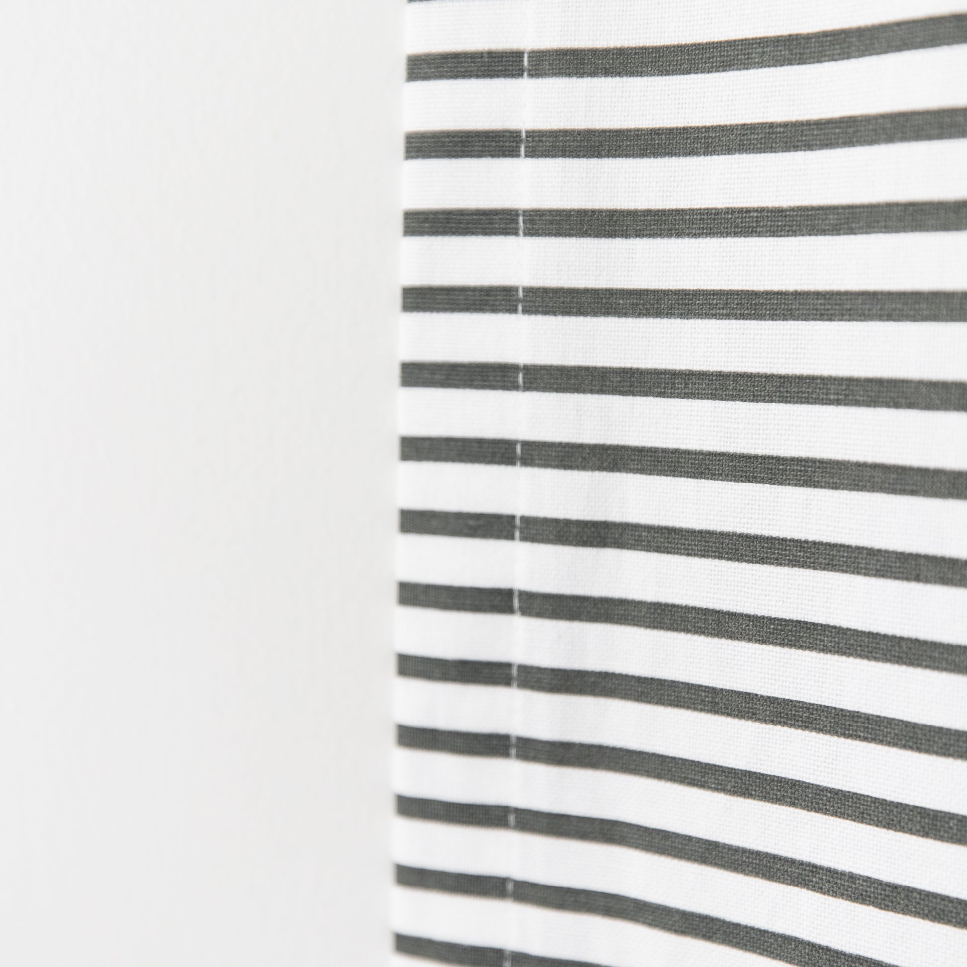White curtain panel with evenly spaced horizontal gray stripes and center seam.