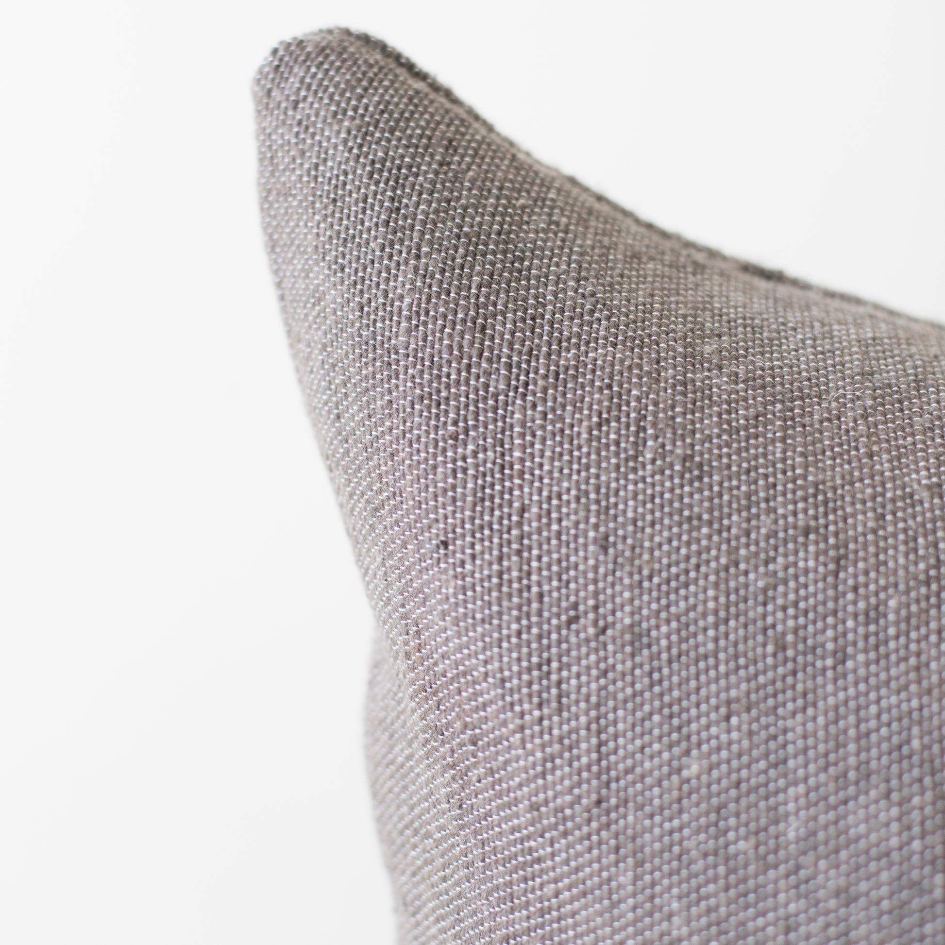 Gray woven textile pillow with textured fabric surface and pointed corner detail.