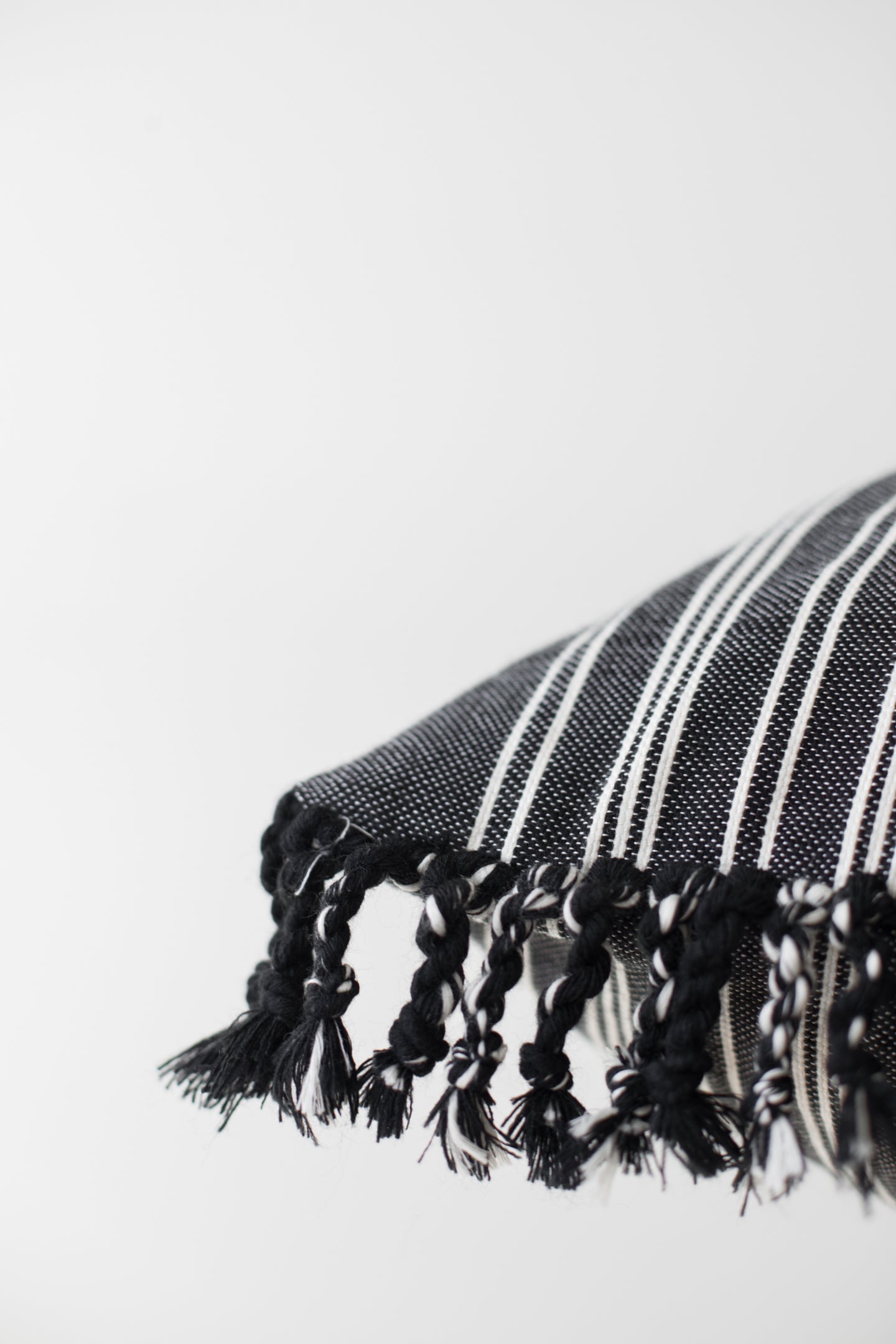 Black and white striped textile with knotted fringe trim along the edge.