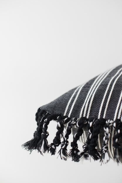 Black and white striped textile with knotted fringe trim along the edge.