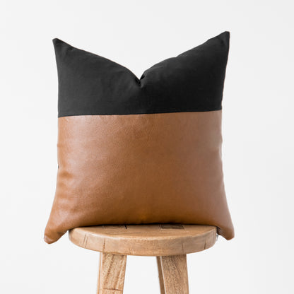 Black and tan two-tone cushion cover with pointed corners, displayed on a wooden stool.