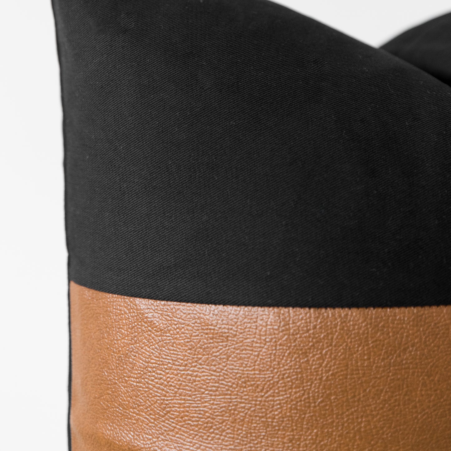 Black canvas and tan leather color-blocked tote bag with structured shape and curved handles.