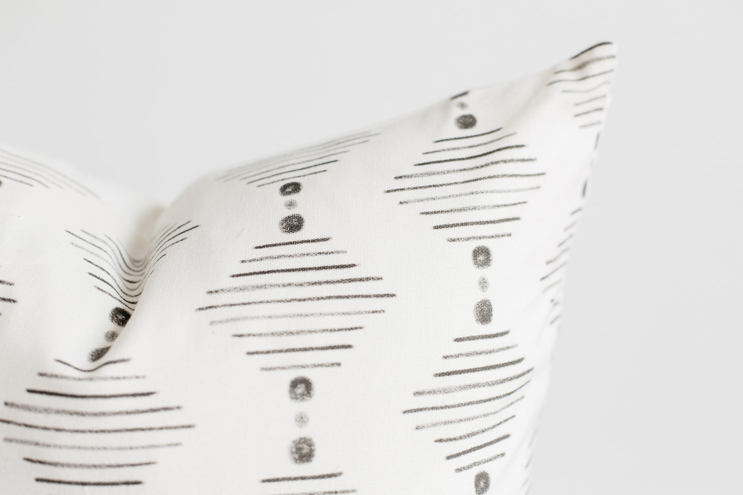 Four white pillows with gray horizontal lines and circular dot patterns arranged in a stack.