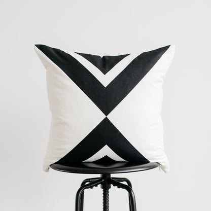 White and black geometric patterned pillow displayed on a black industrial stool.