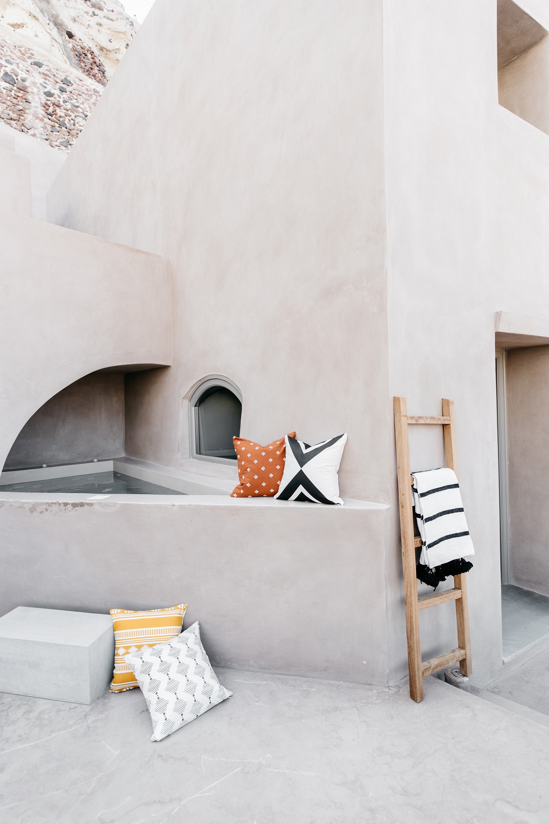 Four decorative pillows in various patterns including orange polka dot, black and white geometric, yellow striped, and white 