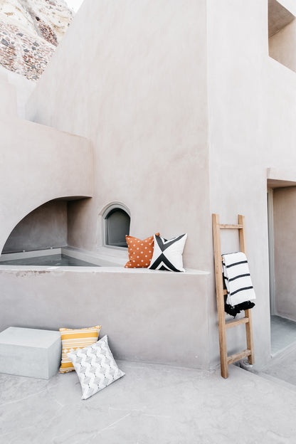 Four decorative pillows in various patterns including orange polka dot, black and white geometric, yellow striped, and white 