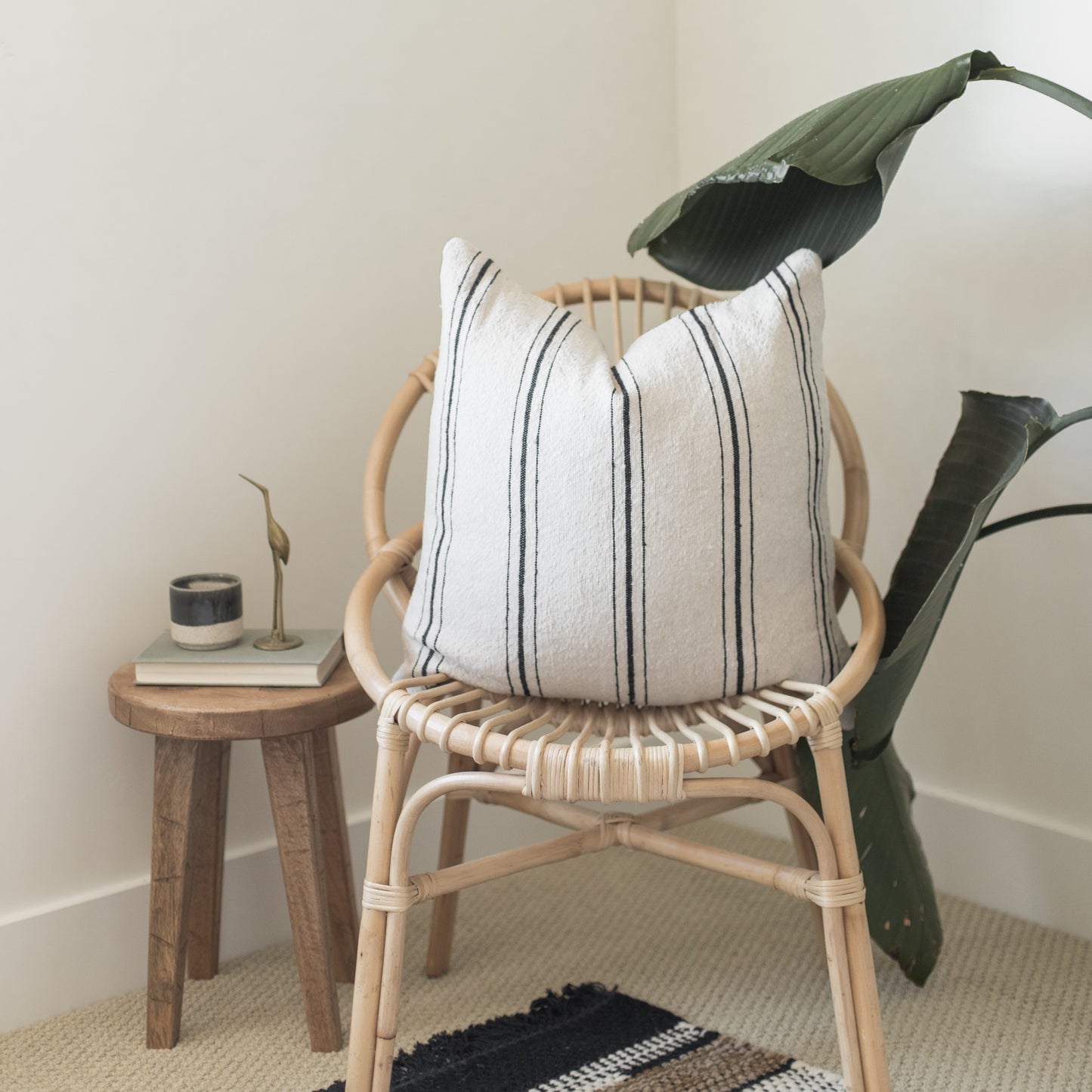 Natural wood rattan chair with white striped pillow and green fabric draped over back.