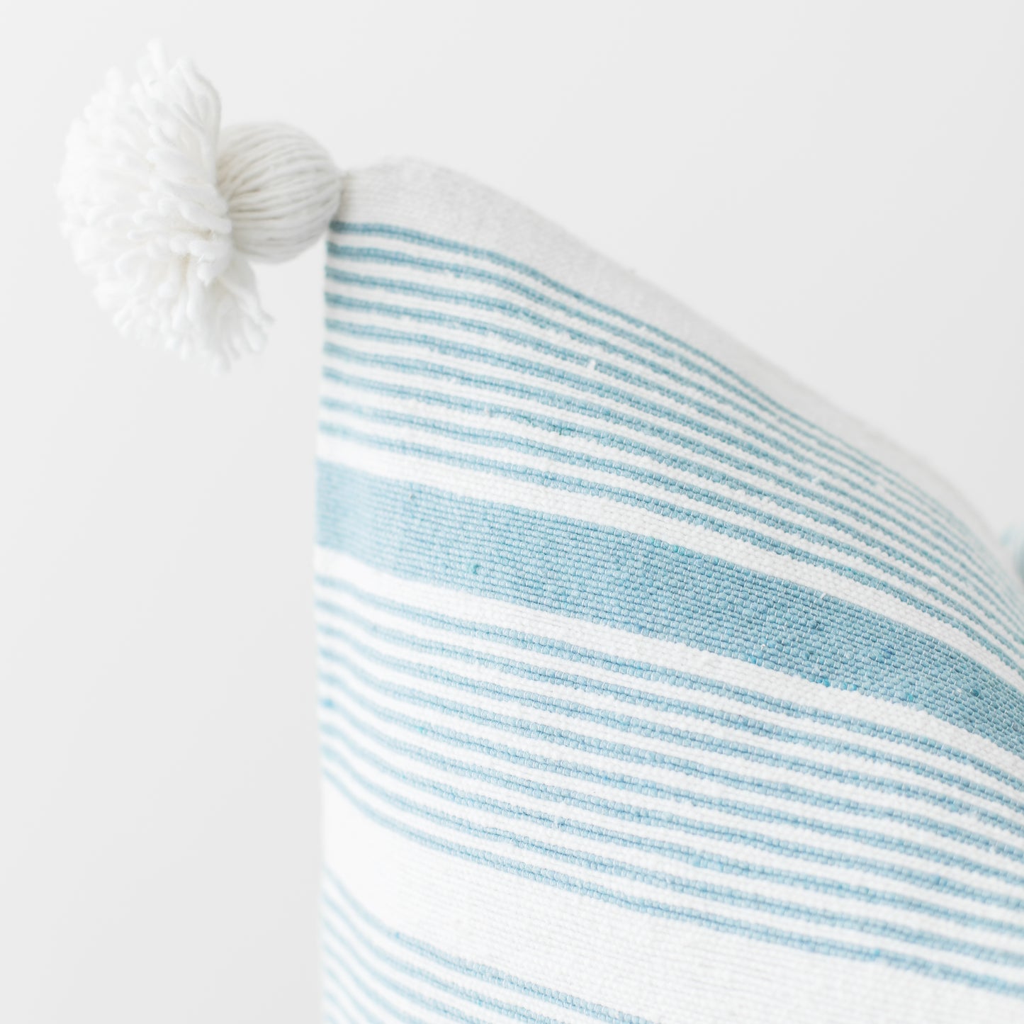 Blue and white striped pillow with white tassel corner detail.