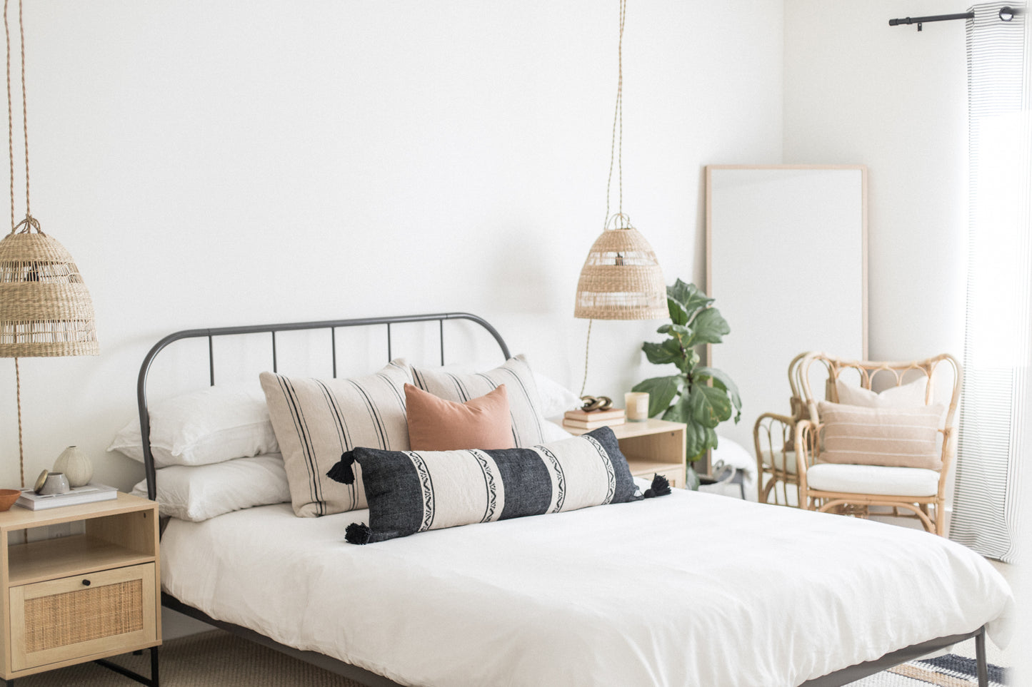 Dark striped lumbar pillow with white panels positioned on bed with white bedding and decorative pillows.