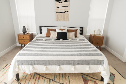 Large striped fez bedding draped across a king/queen size bed with brown and cream pillows.
