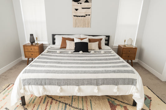 Large striped fez bedding draped across a king/queen size bed with brown and cream pillows.