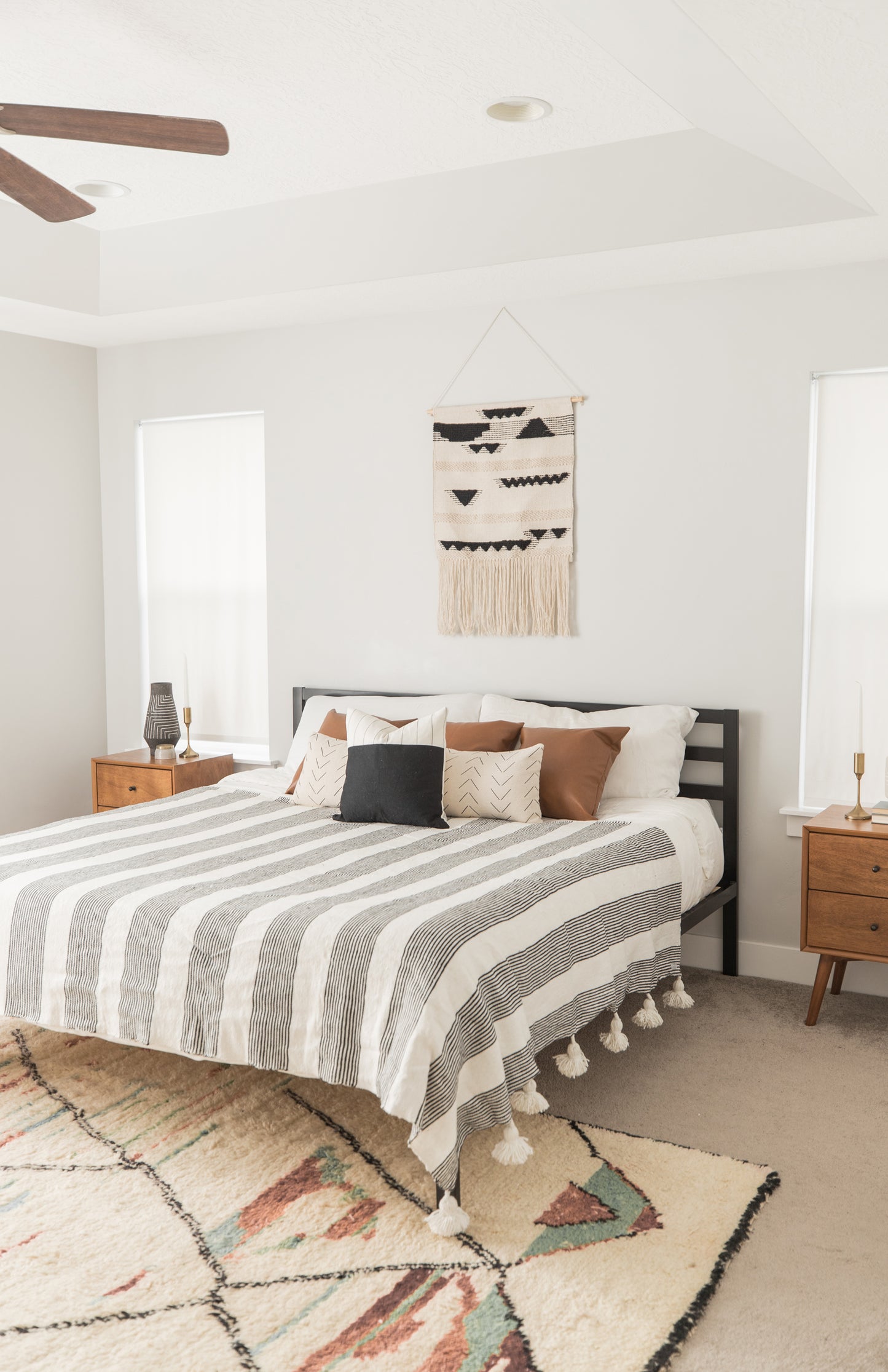 Large striped fez bedspread with fringe trim draped across a king/queen bed in a modern bedroom.