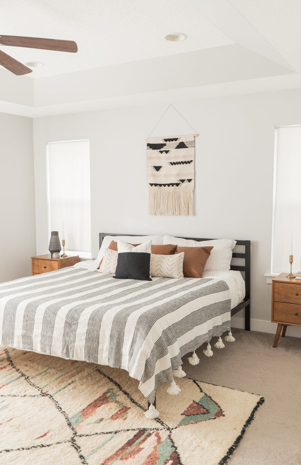 Large striped fez bedspread with fringe trim draped across a king/queen bed in a modern bedroom.