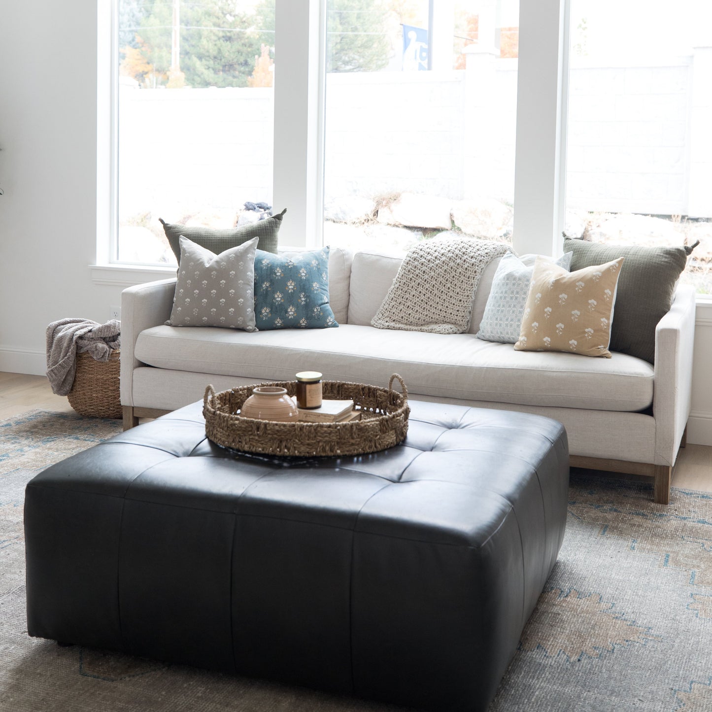 Four 18-inch decorative pillows with varied patterns in gray, blue, cream, and tan displayed on a white sofa.