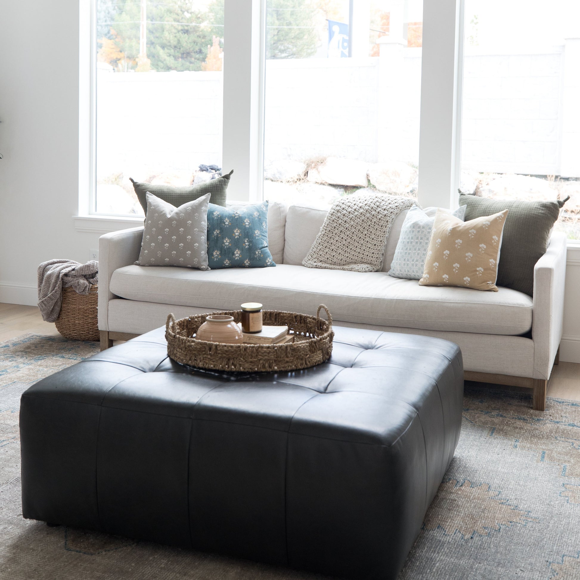 Four 18-inch decorative pillows with varied patterns in gray, blue, cream, and tan displayed on a white sofa.