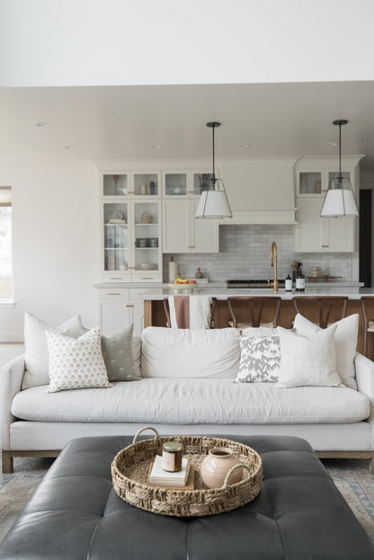 Four decorative pillows with floral and textured patterns arranged on a cream-colored sofa.