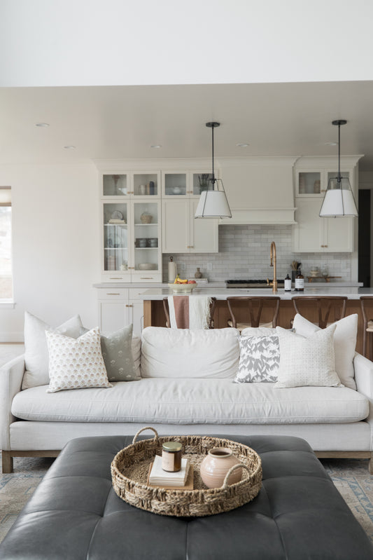 Four decorative pillows with floral and textured patterns arranged on a cream-colored sofa.