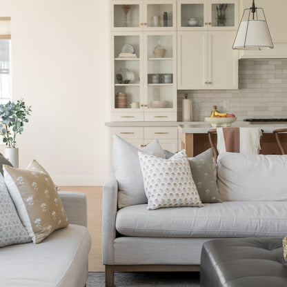 Gray linen sofa with floral and geometric patterned throw pillows in neutral tones.