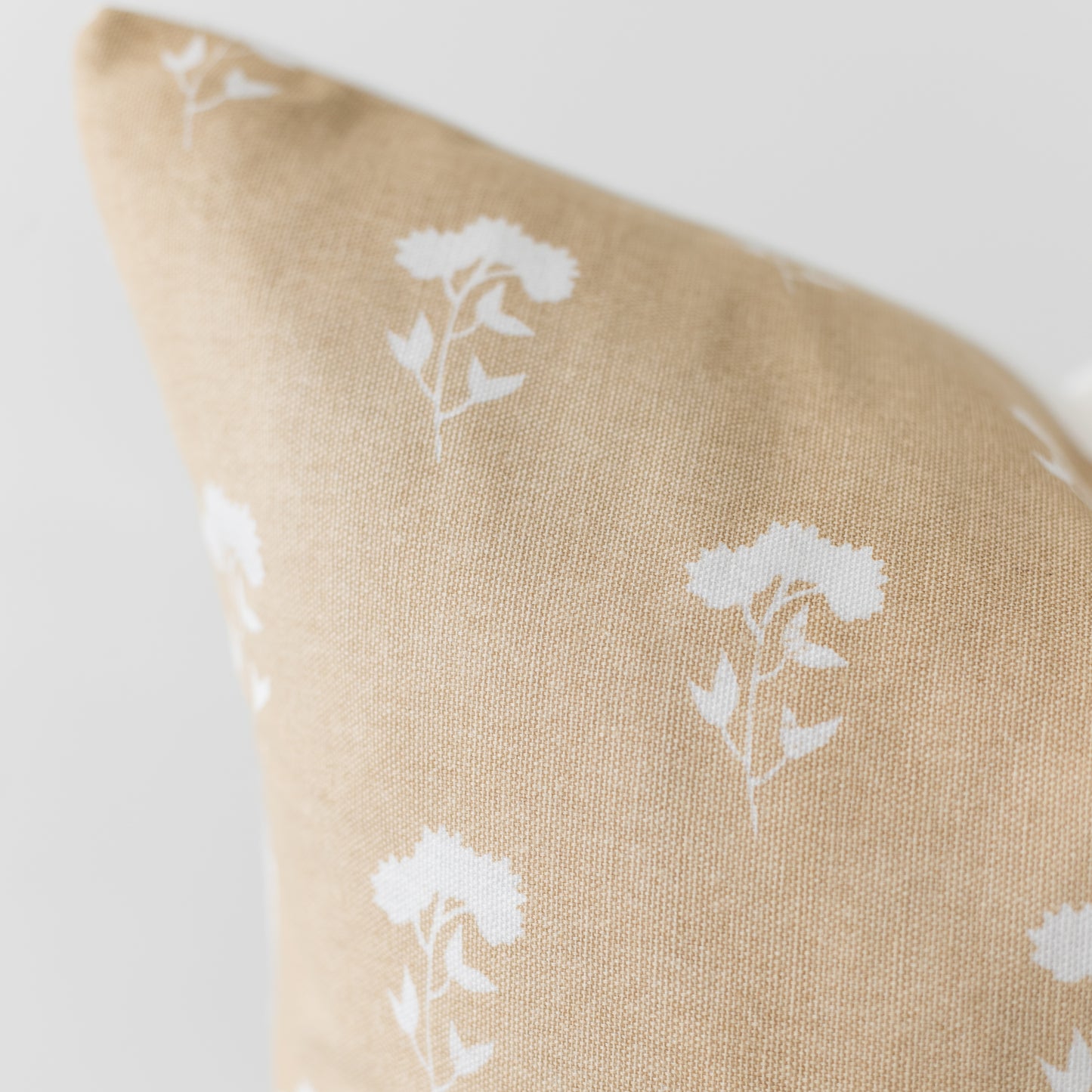 Beige linen pillow cover with white floral botanical print pattern.