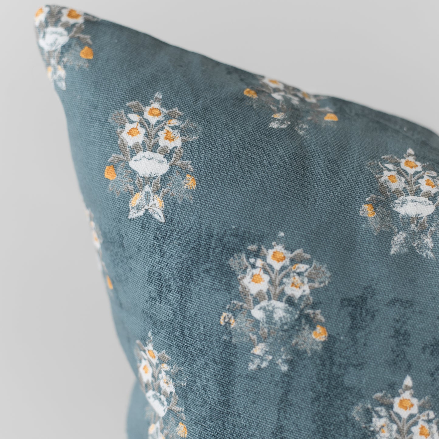 Teal pillow with white and orange floral pattern, 18 inches.