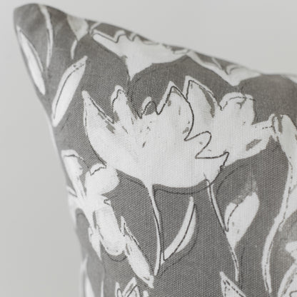 Gray and white pillow with outlined floral pattern on textured fabric.