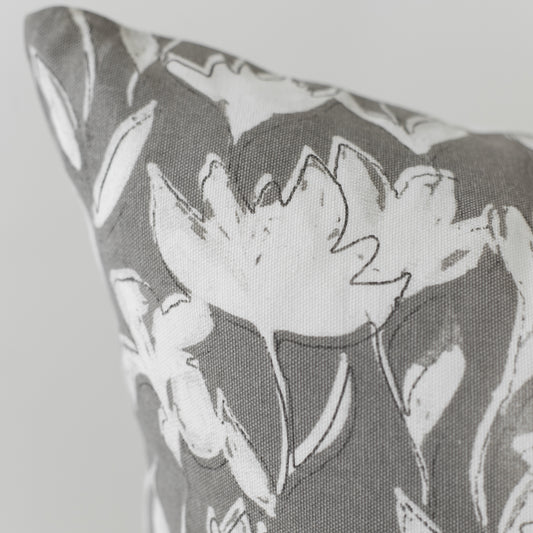 Gray and white pillow with outlined floral pattern on textured fabric.