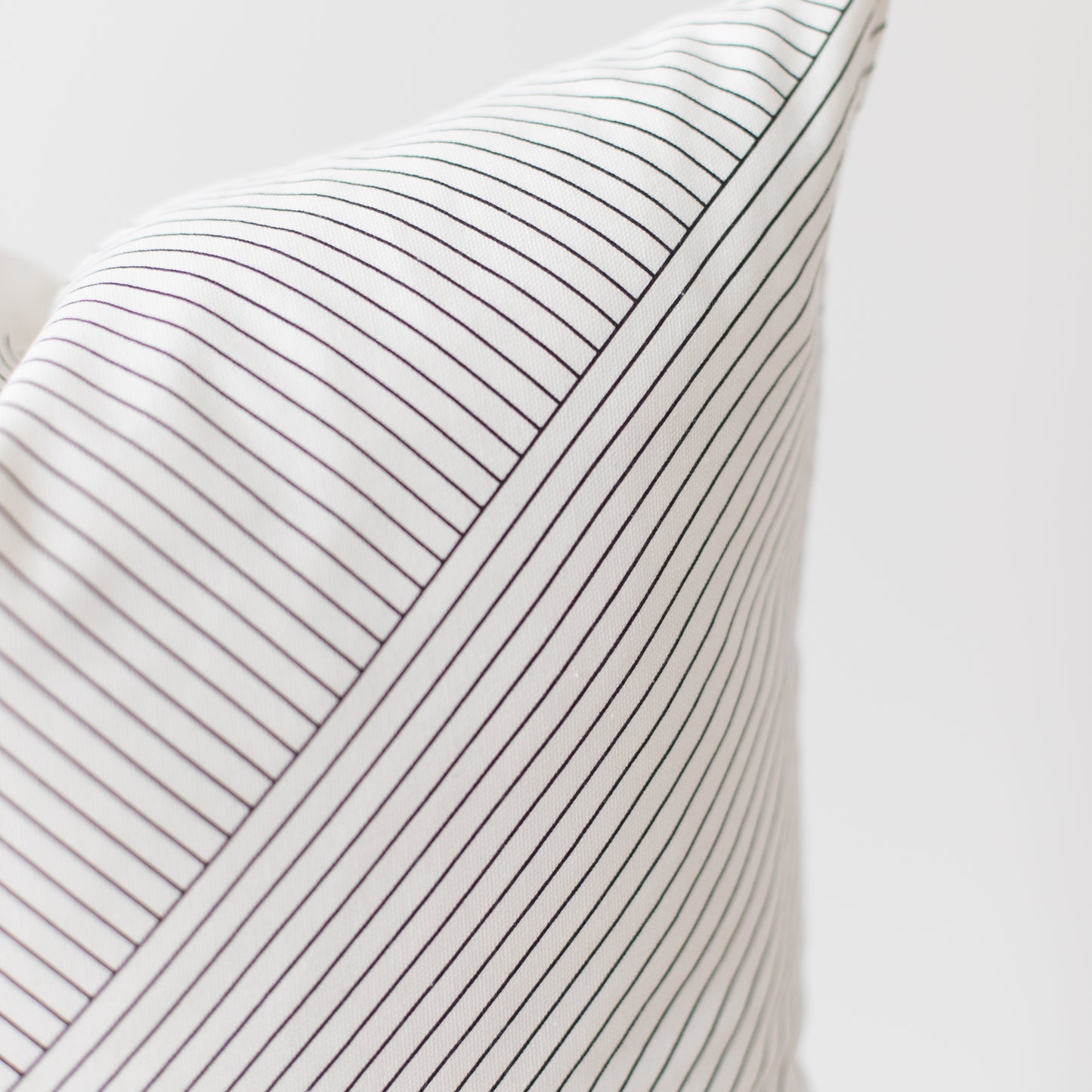 White pillow with thin dark gray pinstripes and ribbed texture.