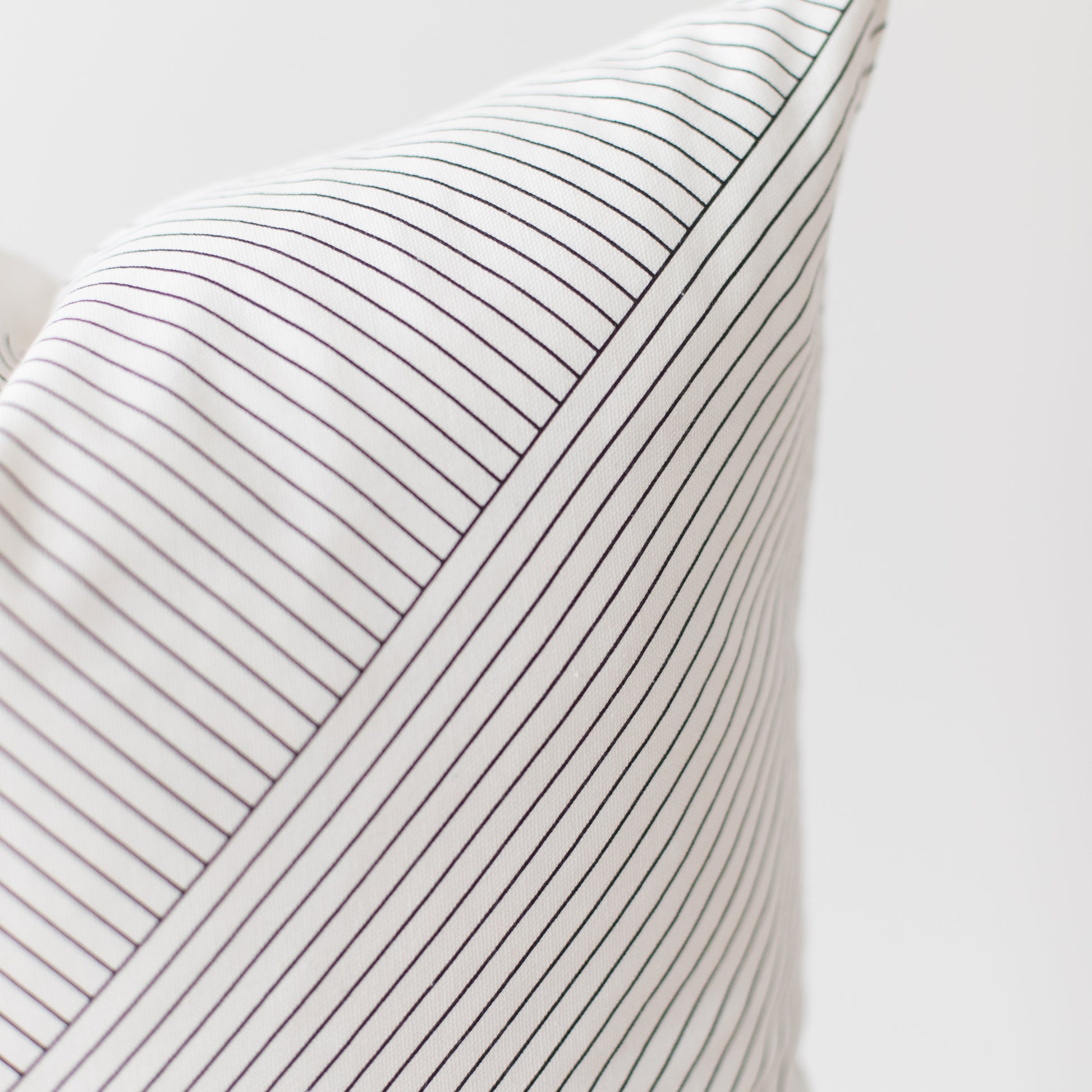 White pillow with thin dark gray pinstripes and ribbed texture.