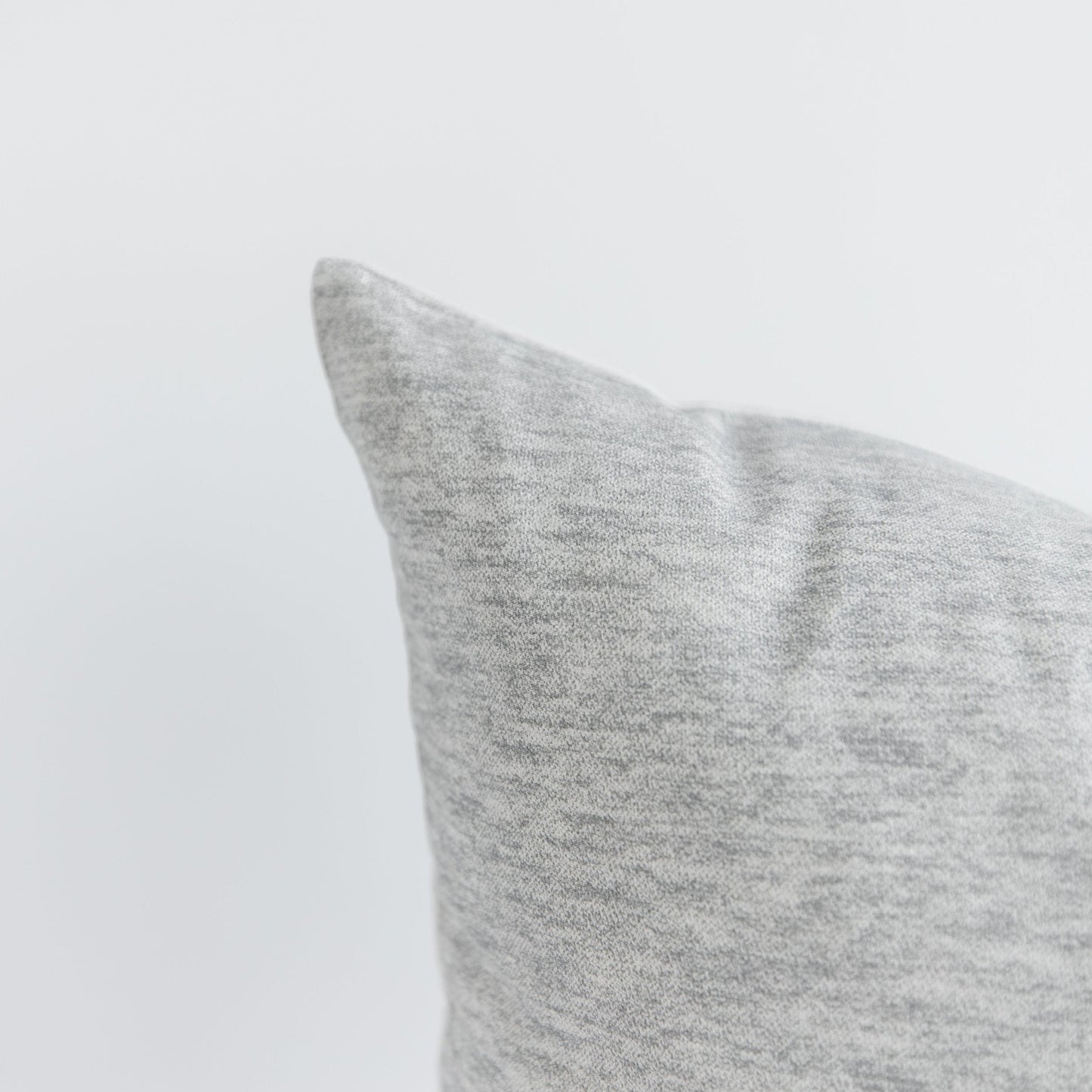 Light gray knit pillow with a soft, textured surface and rounded corner visible against a white background.