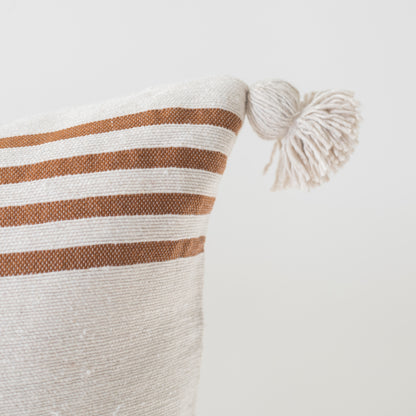 Cream cushion with tan horizontal stripes and cream corner tassels, 22 inches.