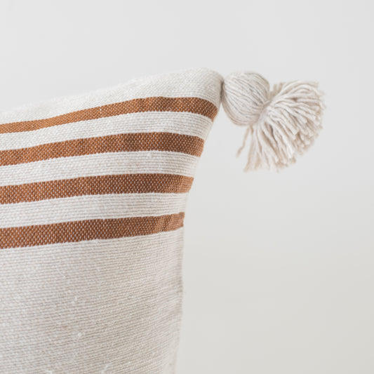 Cream cushion with tan horizontal stripes and cream corner tassels, 22 inches.