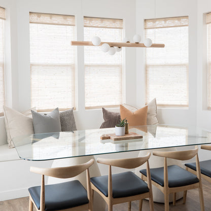 Linear pendant with natural wood bar and white spherical shades suspended above dining table.