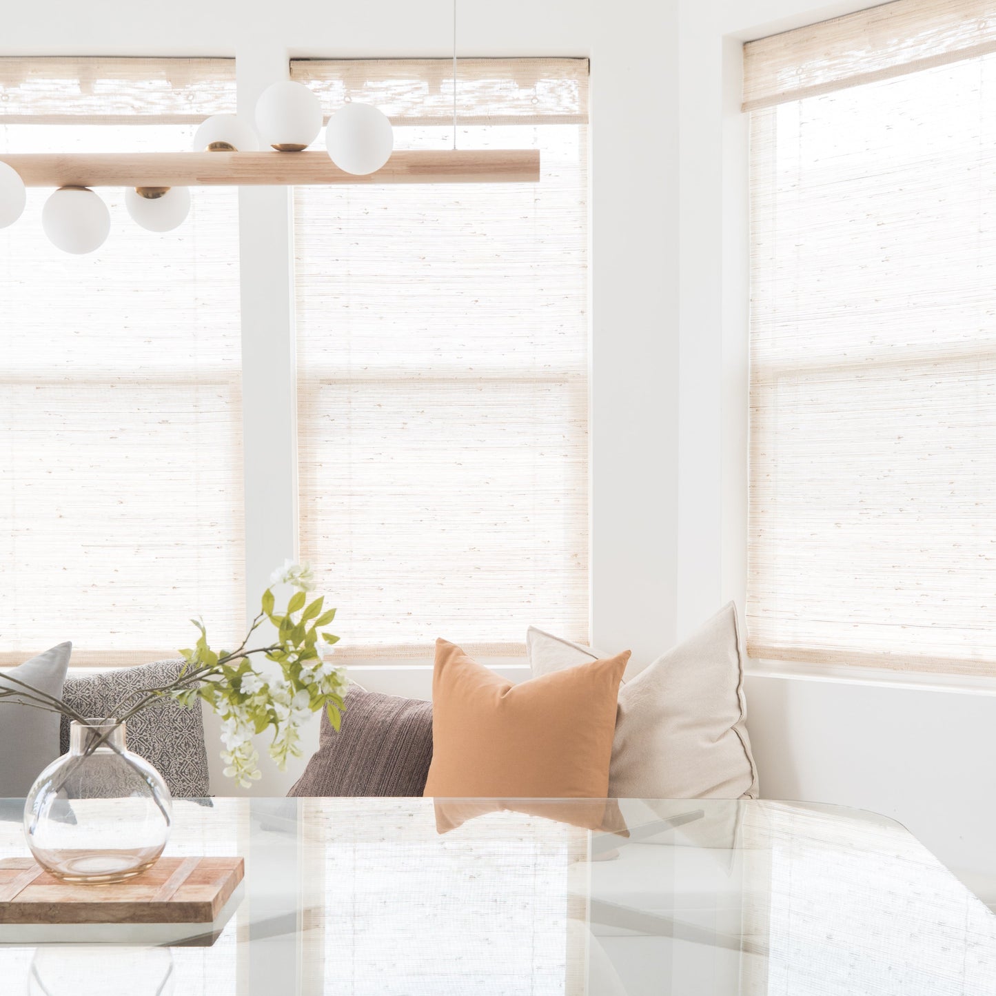 Terracotta-colored square throw pillow on white seating by bright window with natural décor.