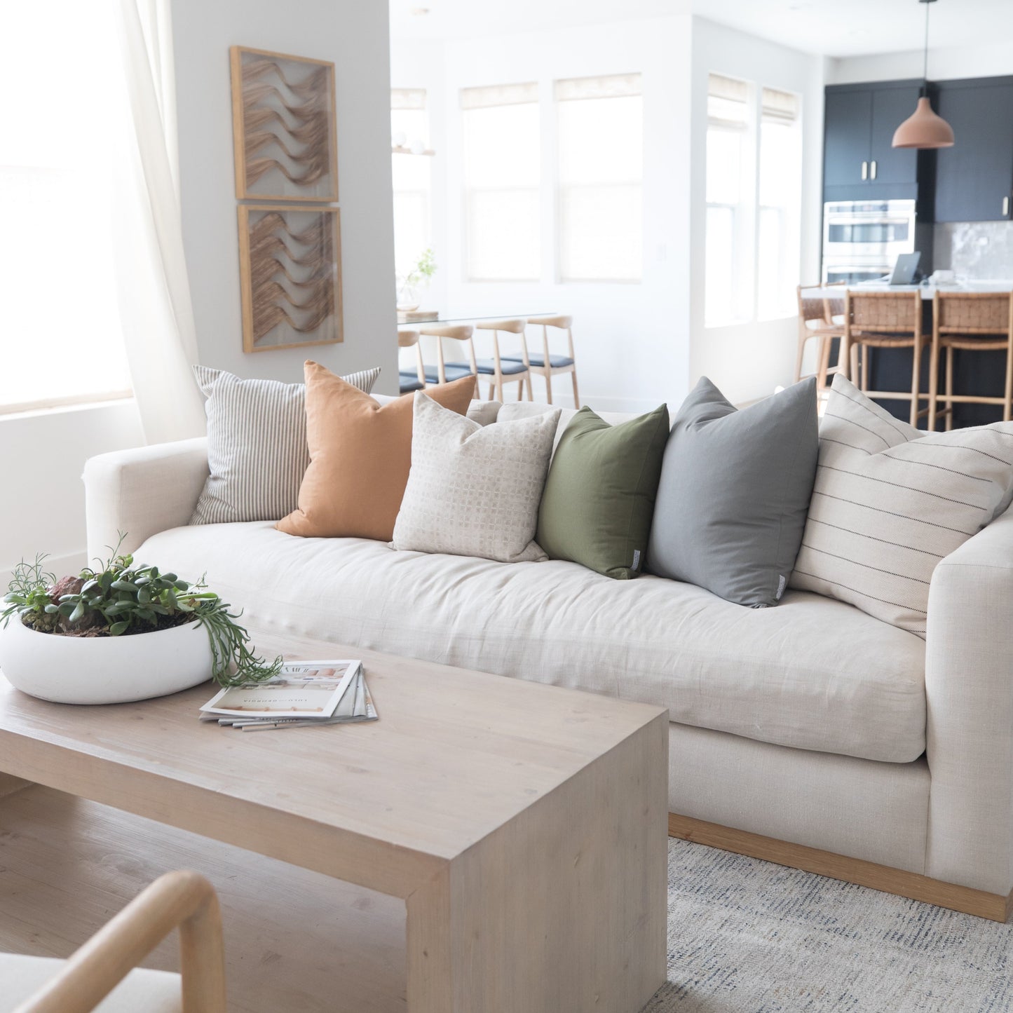 Cream linen sofa with terracotta, beige, sage, and gray throw pillows in a modern living room.