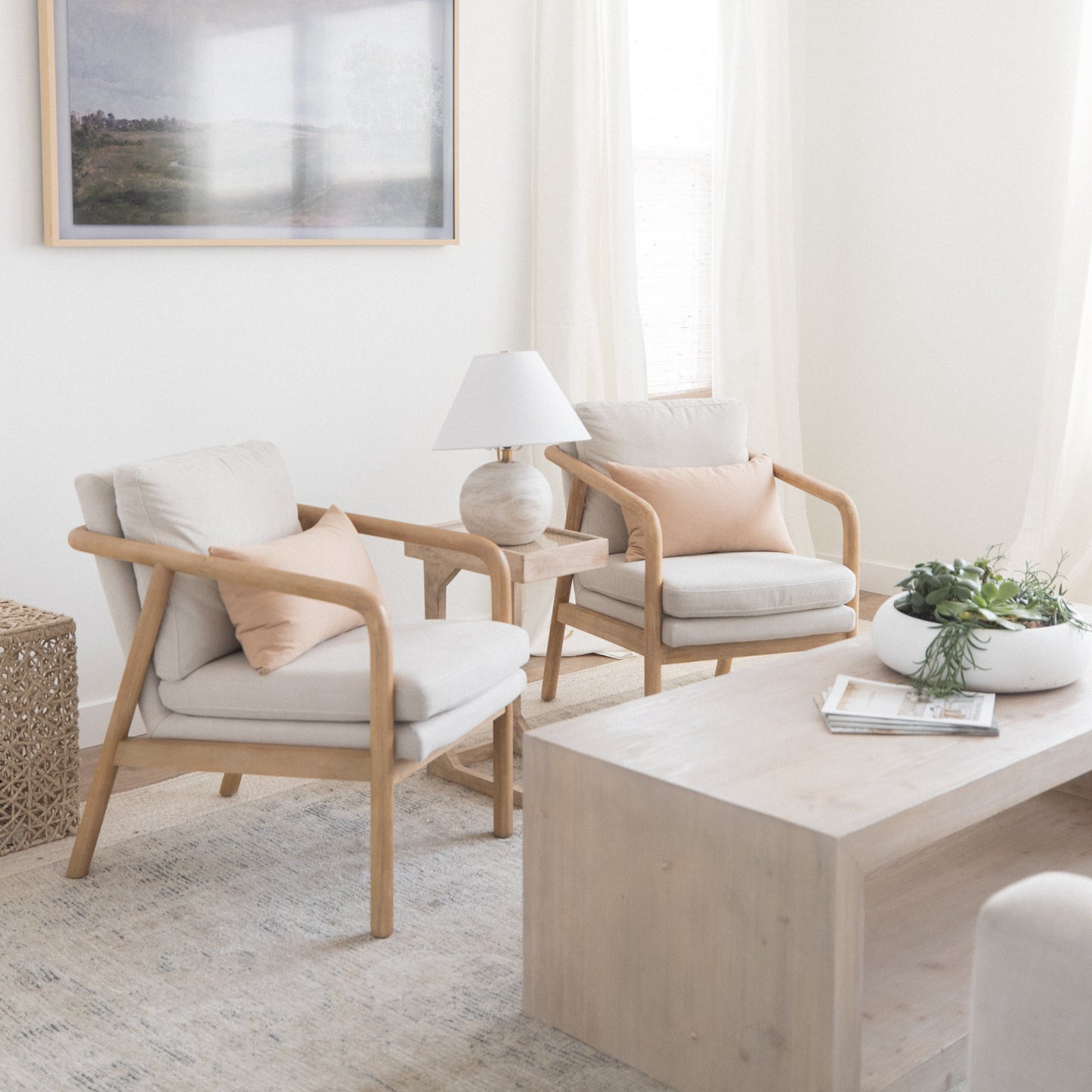 Framed landscape artwork with natural wood frame hanging above modern living room seating area.