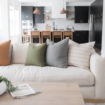 Cream upholstered sofa with tan, sage green, and gray decorative pillows in a modern living room.