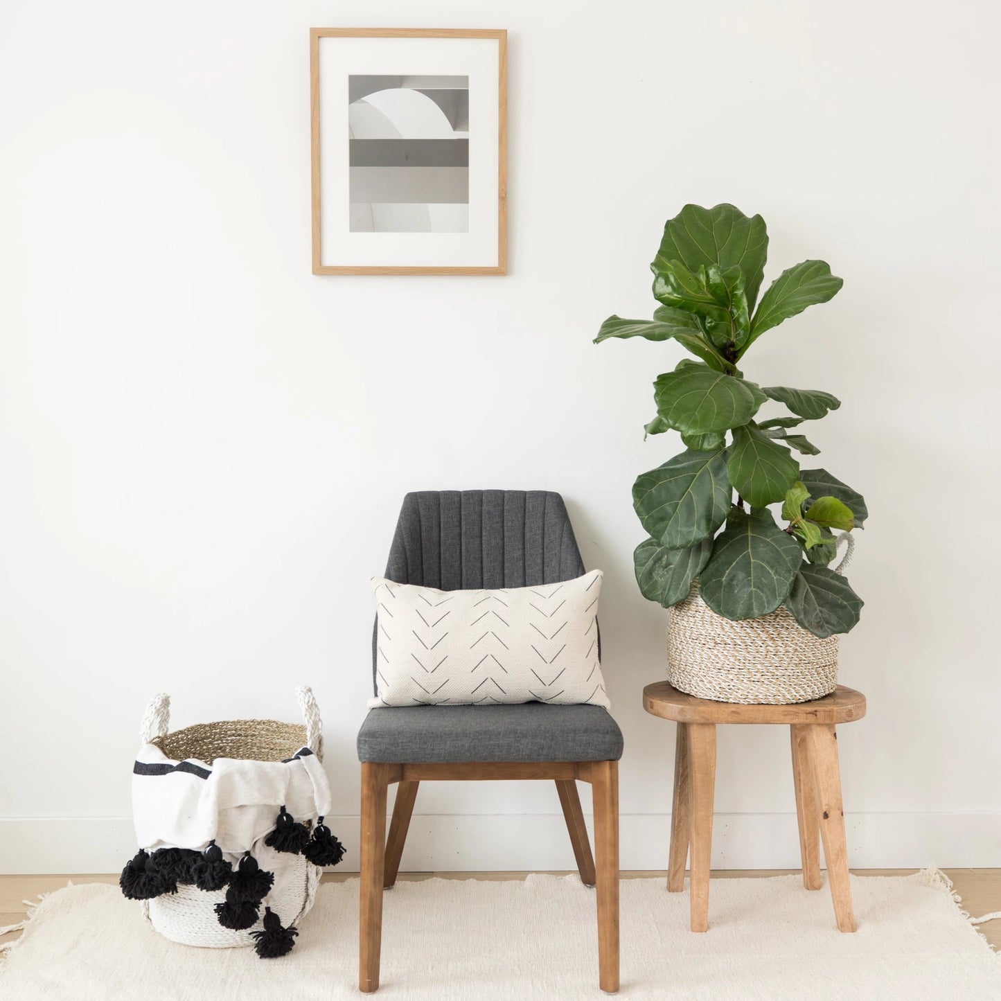 Cream lumbar pillow with chevron pattern displayed on wooden chair with gray cushion.
