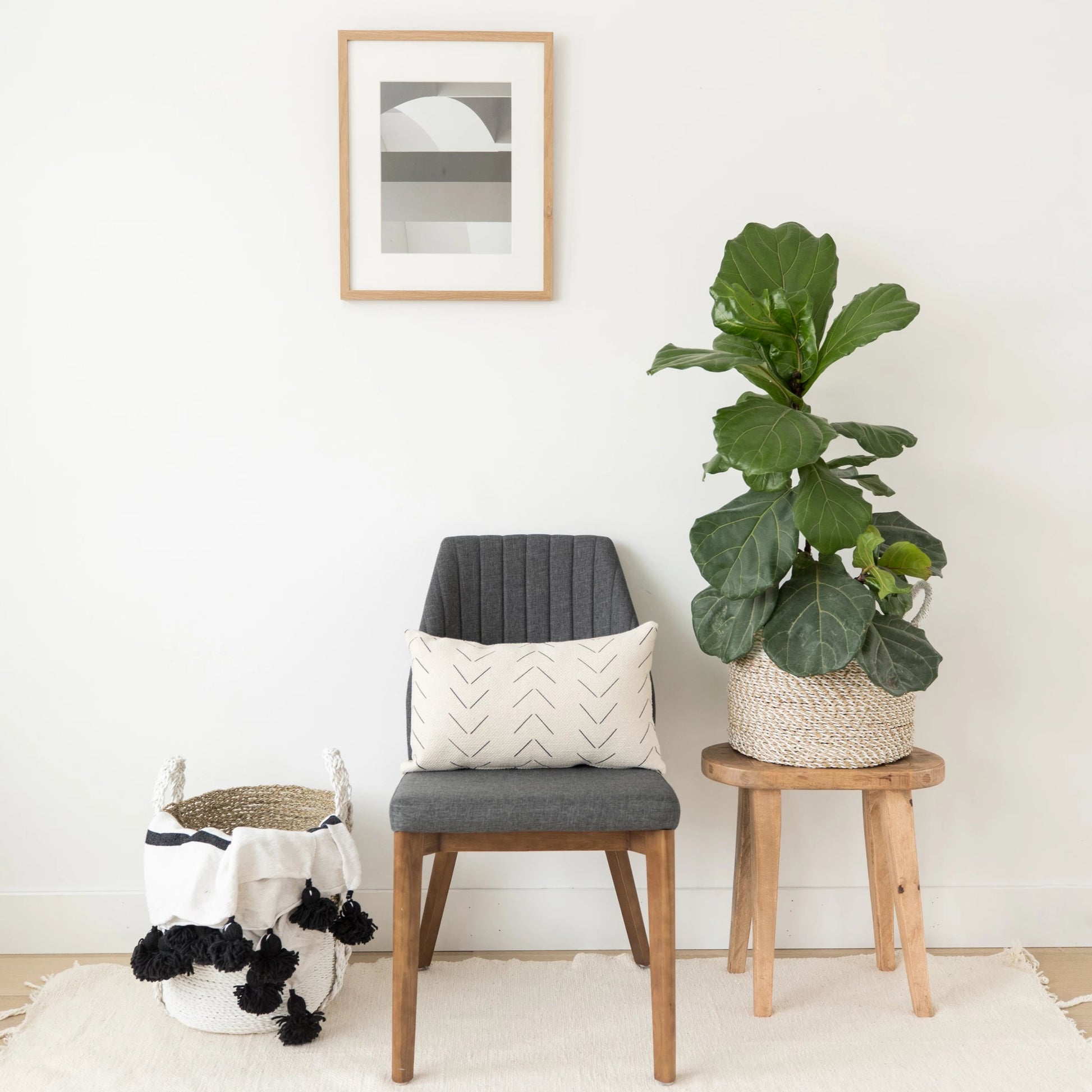 Cream lumbar pillow with chevron pattern displayed on wooden chair with gray cushion.